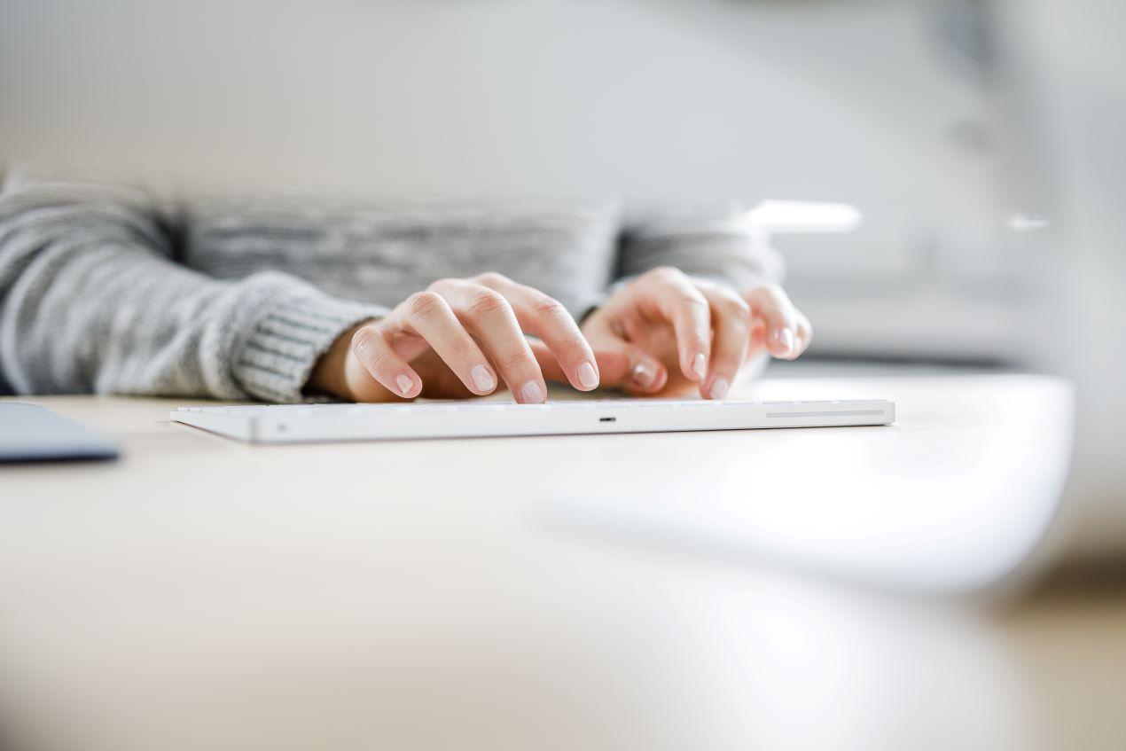 Hände tippen auf einer Tastatur als Symbol für das Schreiben einer Bachelorarbeit mit Unterstützung durch Tools oder einen Bachelor Ghostwriter.